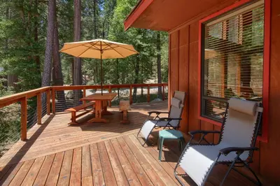 a deck with chairs and a table and an umbrella at 92R Jolie Cabin in North Wawona