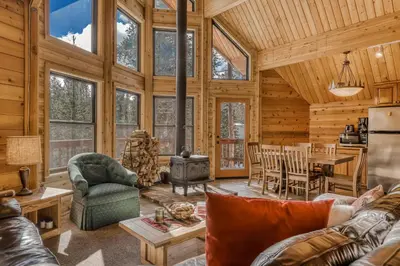 a log cabin living room with a table and a kitchen at Soda Springs Surprise in Soda Springs