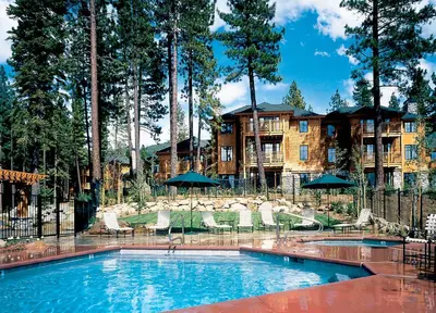 a swimming pool with chairs and umbrellas in front of a building at Hyatt Vacation Club at High Sierra Lodge in Incline Village