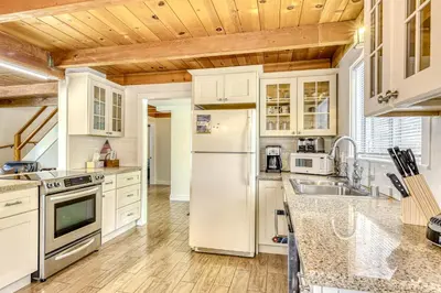 a kitchen with white appliances and a wooden ceiling at Flicker Retreat in Homewood