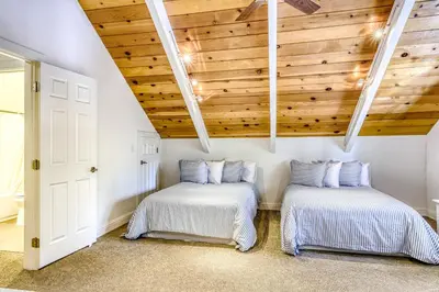 two beds in a room with wooden ceilings at Flicker Retreat in Homewood