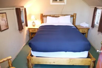 a bedroom with a large bed with a blue blanket at Yosemite Bug Rustic Mountain Resort in Midpines