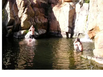 two men are in the water in a river at Yosemite Bug Rustic Mountain Resort in Midpines