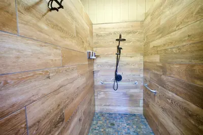 a bathroom with wooden walls and a shower stall at Yosemite Bug Rustic Mountain Resort in Midpines