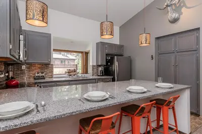a kitchen with a large counter with orange chairs at Helios 11N in Mammoth Lakes
