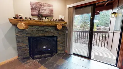 a living room with a fireplace and a balcony at Mammoth Estates 2 Bedroom Condos Near Mammoth Village in Mammoth Lakes