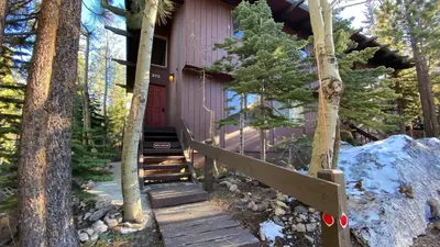 a house in the woods with a wooden staircase leading to it at 2 Bedroom Condos at Mammoth Estates - Near Mammoth Village! in Mammoth Lakes
