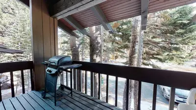 a balcony with a grill on a porch with trees at Mammoth Estates Deluxe 2 Bedroom Condos in Mammoth Lakes
