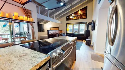 a kitchen with a stove top oven next to a living room at Mammoth Estates Studio Condos 2 Blocks from The Village Gondola Station in Mammoth Lakes