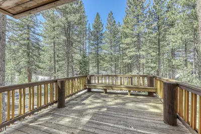 a wooden deck with a bench in the woods at Northstar Gold Bend Retreat in Truckee