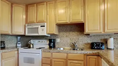 a kitchen with wooden cabinets and a sink and a microwave at 2 Bedroom Townhome With Easy Access to Mountain Biking & Lake Activities - Unit 531 at 1849 condo in Mammoth Lakes