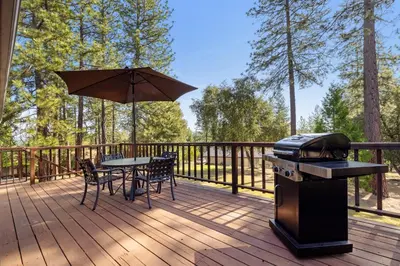 a deck with a grill and a table with chairs and an umbrella at Mountain Springs Lodge in Groveland