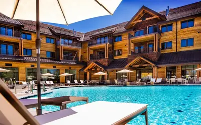a resort pool with tables and chairs and umbrellas at Luxury Three Bedroom Residence steps from Heavenly Village condo in South Lake Tahoe