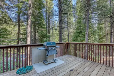 a grill on a wooden deck in the woods at Echo Escape in South Lake Tahoe