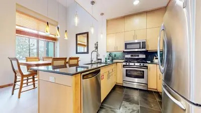 a kitchen with a stainless steel refrigerator and a table at Solstice #18 condo in Mammoth Lakes