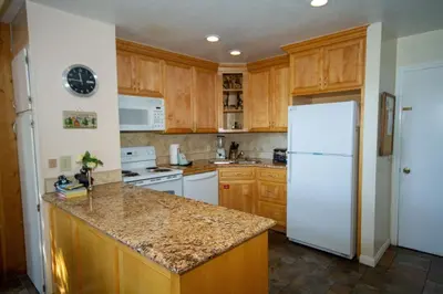 a kitchen with wooden cabinets and a white refrigerator at Mammoth Ski Racquet Club 55 in Mammoth Lakes