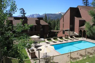 a pool with chairs and umbrellas at a hotel at Mammoth Ski Racquet Club 127 in Mammoth Lakes