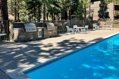 a swimming pool with a grill and tables and chairs at Summit 80 in Mammoth Lakes