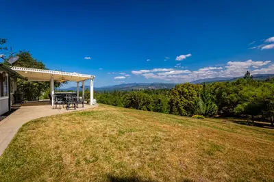 a house with a patio with a view of the mountains at Spectacular Views w/ Hot Tub/BBQ -Yosemite & Bass Lake in Oakhurst
