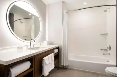 a bathroom with a sink and a tub and a mirror at Courtyard by Marriott Fresno Clovis in Clovis