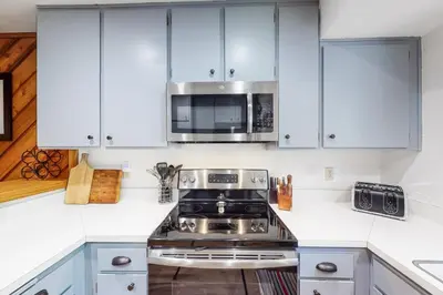 a kitchen with white cabinets and a stove and a microwave at Lake Therapy in Lakeshore