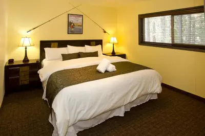 a bedroom with a large bed with white sheets and a window at Holiday Haus in Mammoth Lakes