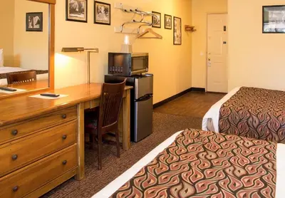 a hotel room with a bed and a desk with a microwave at Holiday Haus in Mammoth Lakes