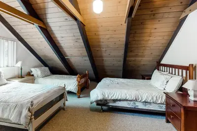 two beds in a attic room with wooden walls at Snowpeak Chalet in Camp Connell
