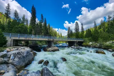 a bridge over a river with rushing water at Snowpeak Chalet in Camp Connell