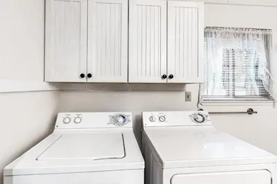 a kitchen with white cabinets and a washer and dryer at Snowpeak Chalet in Camp Connell