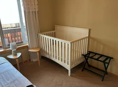 a crib in a bedroom with a bed and a window at Truckee Treat in Truckee