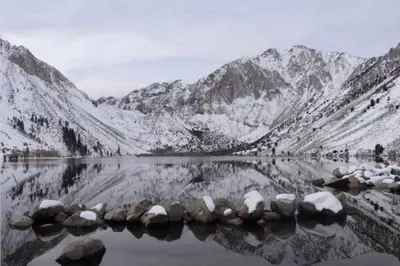 a reflection of snow covered mountains in a lake at Comfy, Quiet, Condo near Lake Mary and the Village in Mammoth Lakes