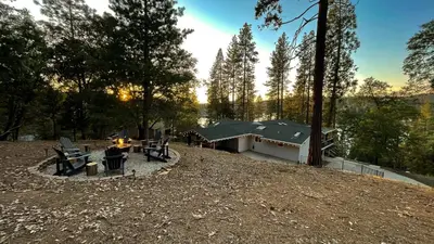 a group of picnic tables and a building in the woods at Cozy mountain retreat with lake views near Yosemite in Groveland