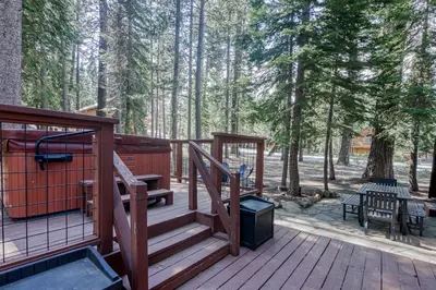 a wooden deck with a grill and stairs in the woods at Hammock Holidays in Truckee