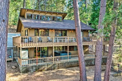 a large wooden house in the woods with trees at Pine Mountain Cabin with Hot Tub, 2 Mins to Marina! in Groveland