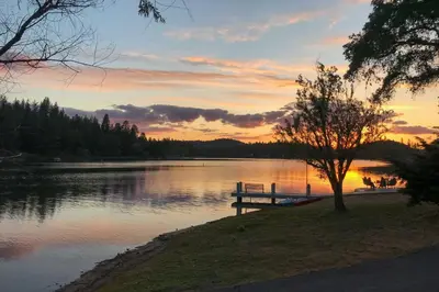 a bench on the shore of a lake at sunset at Cabin Less Than Half-Mi from Pine Mountain Lake Marina! in Groveland