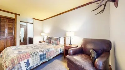 a bedroom with a bed and a leather chair at Mammoth Estates #113 condo in Mammoth Lakes