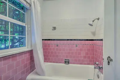 a bathroom with pink tile and a tub and a window at Historic Reno Home on Riverwalk 1 Mi to Midtown in Reno