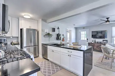 a kitchen with white cabinets and a stainless steel refrigerator at Hot Tub, Fire Pit Midtown Reno Oasis! in Reno