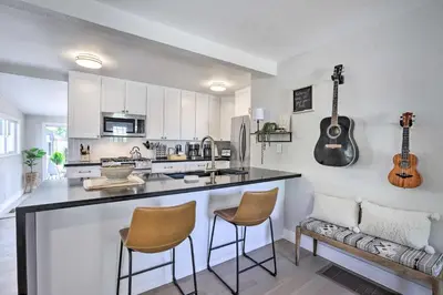 a kitchen with a bar with two chairs and a guitar on the wall at Hot Tub, Fire Pit Midtown Reno Oasis! in Reno