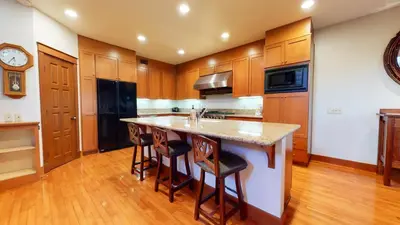 a kitchen with wooden cabinets and a island with bar stools at Timbers #10 townhouse in Mammoth Lakes