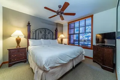 a bedroom with a bed with a ceiling fan and a television at Luxury Oasis Village Ski-in Ski-out in Mammoth Lakes