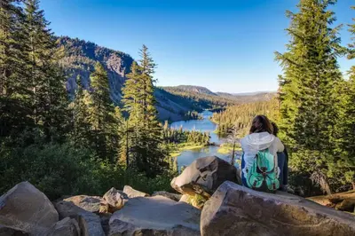 a woman sitting on a rock overlooking a lake at La Residence 8 in Mammoth Lakes