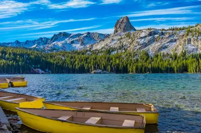 three boats on the shore of a lake with mountains at La Residence 8 in Mammoth Lakes