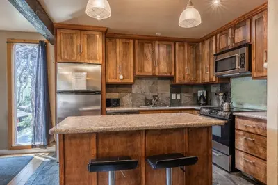 a kitchen with wooden cabinets and a granite counter top at Mammoth Ski Racquet Club 32 - Newly Remodeled Pet Friendly in Mammoth Lakes