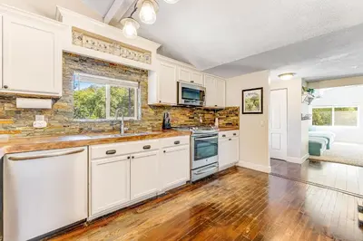 a kitchen with white cabinets and a hardwood floor at Wildcat Family Ranch in Murphys