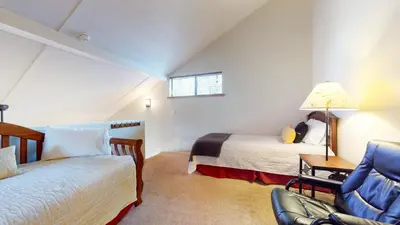 a attic bedroom with two beds and a chair at San Sierra #26 condo in Mammoth Lakes