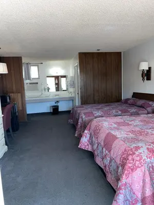 a hotel room with two beds and a sink at El Portal Motel in Beatty