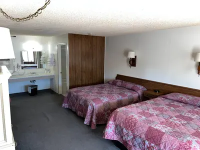 a hotel room with two beds and a sink at El Portal Motel in Beatty