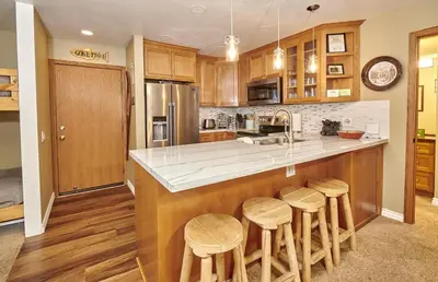 a kitchen with wooden cabinets and a counter with stools at St Anton Street View Ski-In & Out 1-Bedroom Condo in Mammoth Lakes